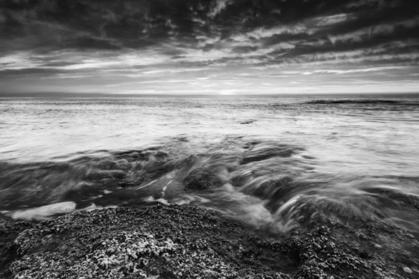 Ein Graustufenbild Von Plätschernden Meereswellen Unter Einem Bewölkten Himmel — Stockfoto
