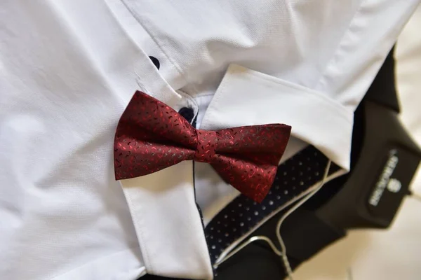 A closeup shot of a red bow tie on a white shirt under the lights - fashion concept