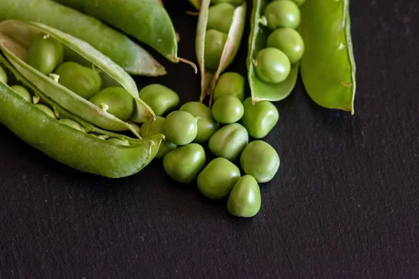 黒の木の背景に新鮮な緑のエンドウ豆の種のクローズアップショット — ストック写真