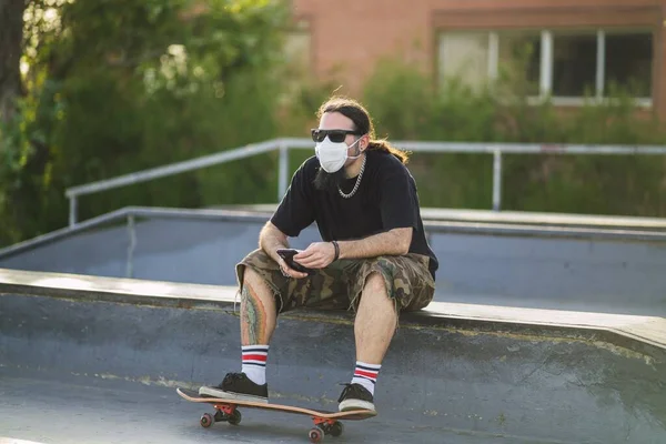 Ένας Νεαρός Άνδρας Κάθεται Ένα Skateboard Στο Πάρκο Φορώντας Μια — Φωτογραφία Αρχείου