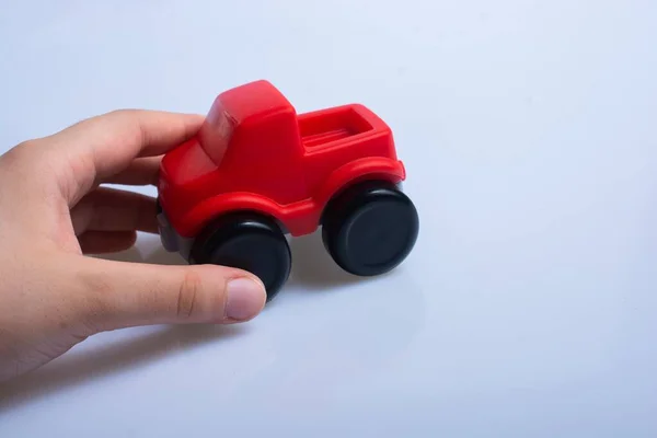 Mão Uma Pessoa Segurando Carro Brinquedo Plástico Vermelho Uma Superfície — Fotografia de Stock