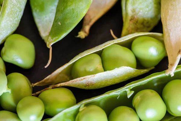 黒の木の背景に新鮮な緑のエンドウ豆の種のクローズアップショット — ストック写真