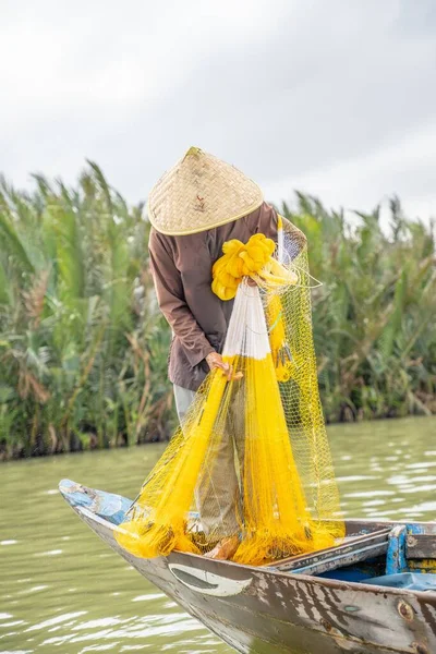 A vertical closeup shot of a Vietnamese fishing with a yellow net in the lake