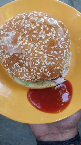 黄色の皿の上に季節のハンバーガーのパンとケチャップのクローズアップ — ストック写真