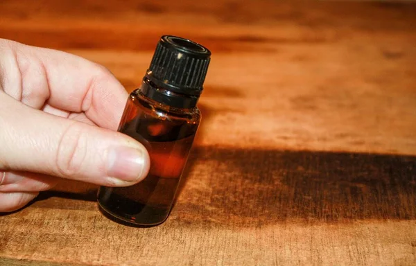 Closeup Shot Male Hand Holding Small Bottle Wooden Table — Stock Photo, Image