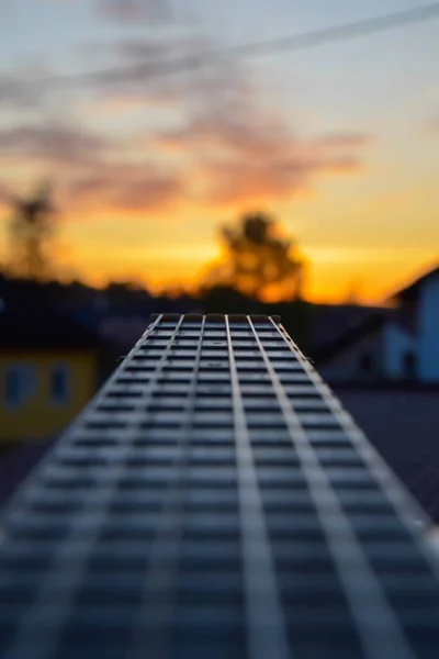 背景に美しい夕日を望むギターの垂直クローズアップショット — ストック写真