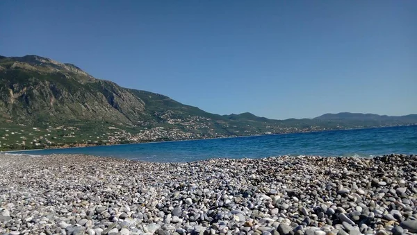 Una Vista Mar Azul Lleno Piedras Con Una Alta Montaña —  Fotos de Stock