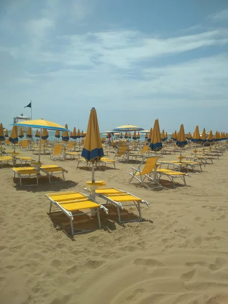 黄蓝相间的雨伞和椅子在阳光下在海滩上垂直拍摄的照片 — 图库照片