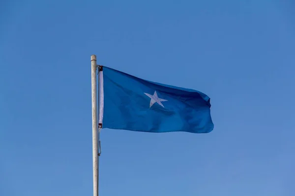 青い空の下で風の中でソマリアの踊りの旗の低角度ショット — ストック写真