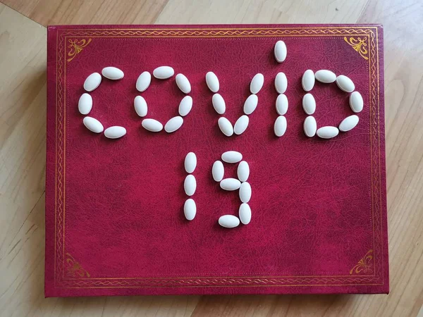 書き込み Covid19 黄金のパターンとバーガンディボード上の白い錠剤で作られた — ストック写真