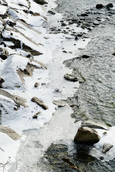 氷の小川の中の雪に覆われた岩の垂直ショット — ストック写真