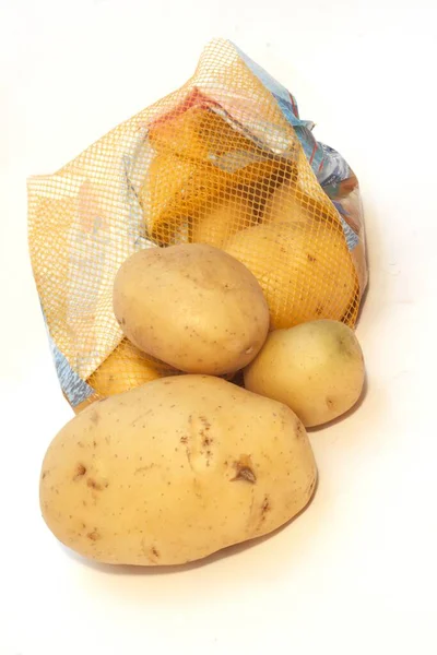 白い背景に隔離されたネットバッグの中の有機ジャガイモ — ストック写真