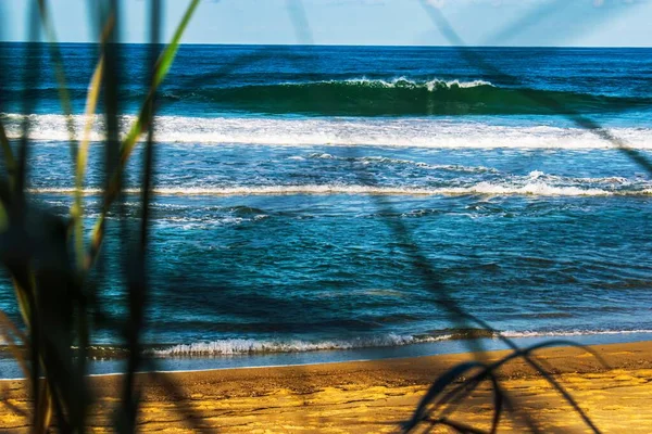 蓝色天空下的波浪形大海和沙滩的选择性聚焦镜头 — 图库照片