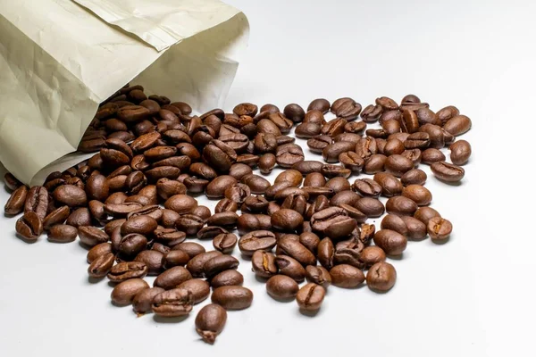 A closeup of a paper bag with roasted coffee beans under the lights isolated on a white background