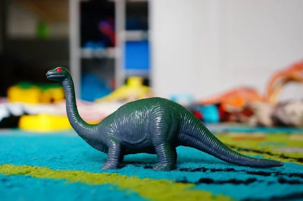 Zbliżenie Sauropoda Zabawka Kolorowym Dywanie Pod Światłami Rozmytym Tłem — Zdjęcie stockowe