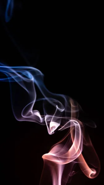 黒い背景に抽象的な形を作るカラフルな煙の垂直ショット — ストック写真