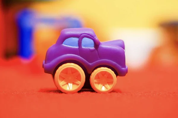Nahaufnahme Eines Kleinen Spielzeugautos Auf Roter Fläche Mit Unscharfem Hintergrund — Stockfoto