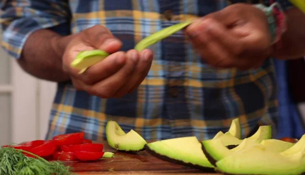 An African-American man\'s hands peeling an avocado