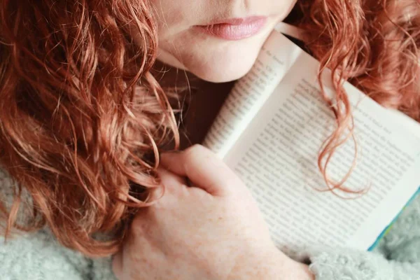 一个红头发的年轻女子在灯光下拿着一本书的特写镜头 — 图库照片