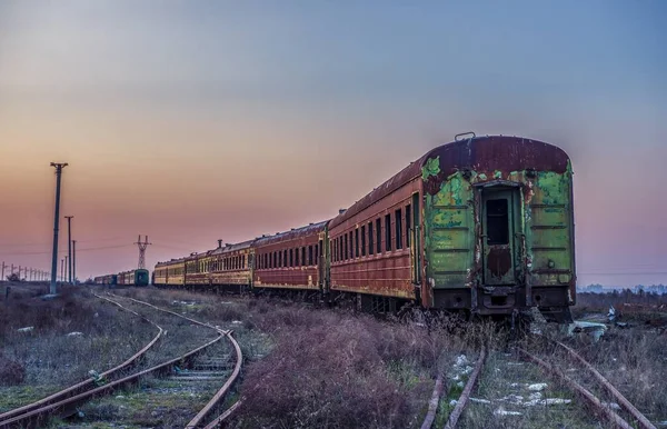 日没の間のレールの上の古い錆びた列車 — ストック写真