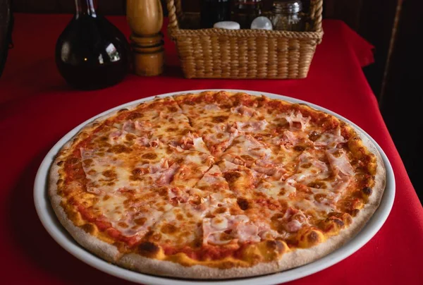 赤いテーブルの上に白いプレートに置かれたピザのクローズアップショット — ストック写真