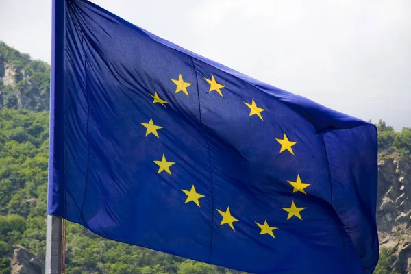 Zbliżenie Falistej Flagi Europy Otoczone Wzgórzami Pokrytymi Zielenią Pod Słońcem — Zdjęcie stockowe