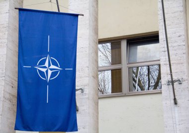 A closeup of the flag of NATO hanging from a building under the sunlight clipart