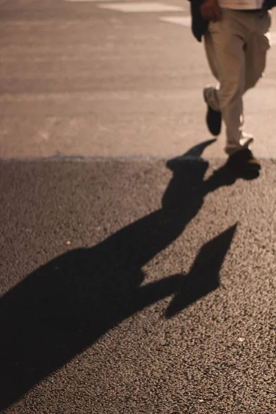 晴れた日にアスファルトの上をジョギングする男の影 — ストック写真