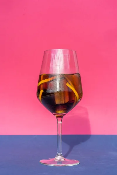 ピンクの背景に緑のオリーブとレモンの皮を持つアルコール飲料の垂直ショット — ストック写真