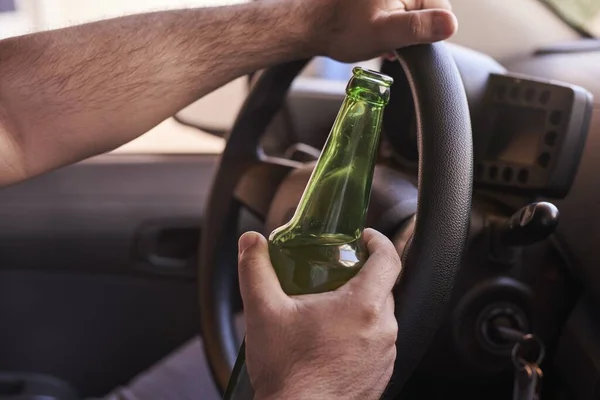一个拿着一瓶啤酒开车的男人 驾驶不安全的概念 — 图库照片