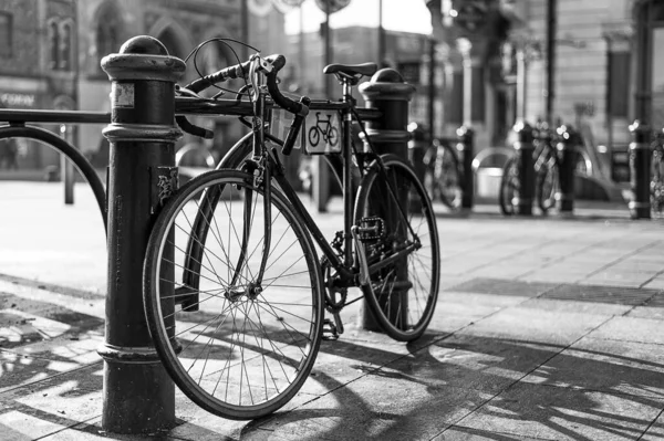 一辆停放在城里一个柱子旁边的自行车的灰度照片 — 图库照片