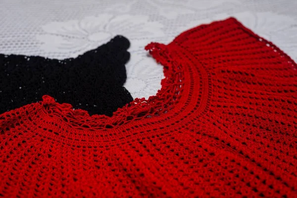 Tiro Close Duas Camisas Crochê Preto Vermelho Uma Superfície Branca — Fotografia de Stock