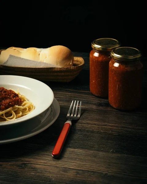 一碗意大利面与面包和两罐酱汁放在桌上的垂直镜头 — 图库照片