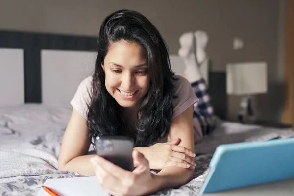 Uśmiechnięta Atrakcyjna Kobieta Korzystająca Smartfona Tabletu Nauki Online Leżąca Łóżku — Zdjęcie stockowe