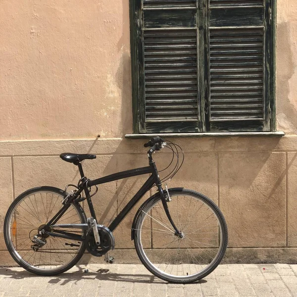 Una Bicicleta Negra Acera Junto Vieja Ventana Madera Edificio Hormigón —  Fotos de Stock