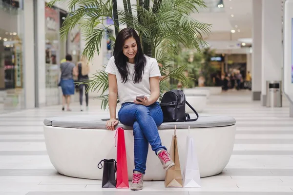 Uma Jovem Mulher Sentada Shopping Olhando Para Celular Com Alguns — Fotografia de Stock