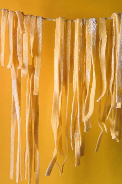 Вертикальный Кадр Нарезанного Теста Свисающий Веревки Желтом Фоне — стоковое фото