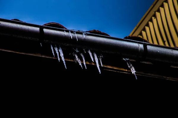冰柱在屋顶金属管上的低角度冰柱拍摄 — 图库照片