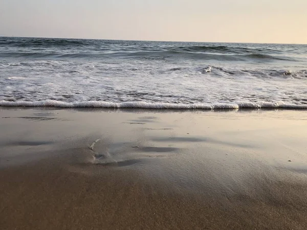 Océan Ondulé Frappant Plage Sable Luisant Sous Ciel Coloré — Photo