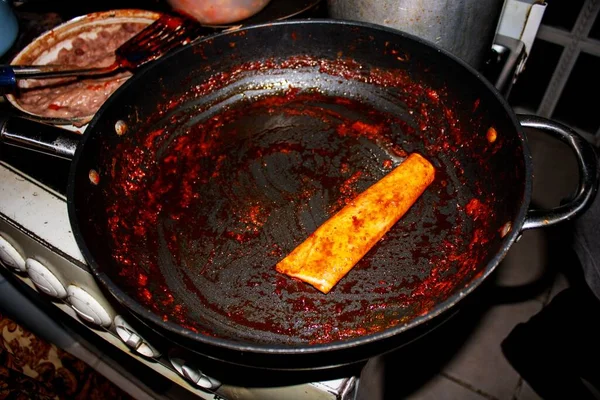 The process of cooking Mexican traditional dish enchiladas with cheese and potatoes