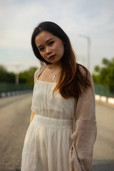 Beyaz Elbiseli Sokakta Poz Veren Asyalı Bir Kadının Dikey Fotoğrafı — Stok fotoğraf