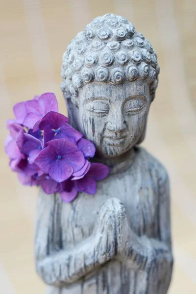 一个有紫色花瓣花的佛像的特写 — 图库照片