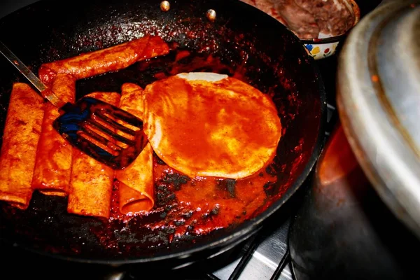 The process of cooking Mexican traditional dish enchiladas with cheese and potatoes