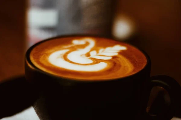 Eine Selektive Fokusaufnahme Einer Schwarzen Tasse Cappuccino Auf Dem Tisch — Stockfoto