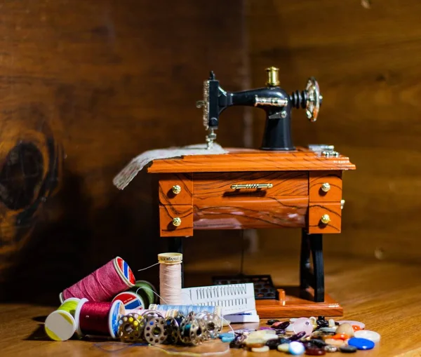 小木桌上的玩具缝纫机 旁边有不同的螺纹和钮扣 — 图库照片