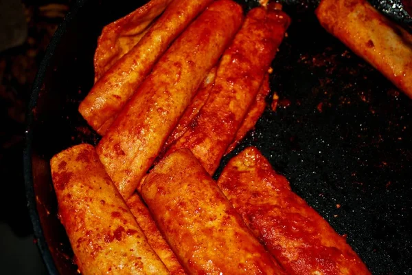 The process of cooking Mexican traditional dish enchiladas with cheese and potatoes