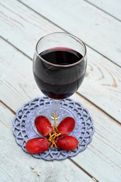 Pionowy Kieliszek Czerwonego Wina Winogronami Drewnianym Stole Pod Światłami — Zdjęcie stockowe