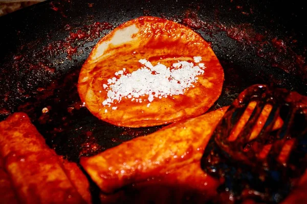 The process of cooking Mexican traditional dish enchiladas with cheese and potatoes