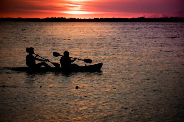 夕阳西下 两个人在平静的大海中划船的轮廓 — 图库照片