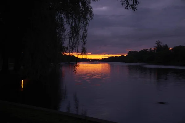 Sjön Glimmar Den Gula Solnedgången Genomträngande Genom Den Molniga Himlen — Stockfoto